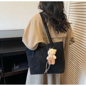 Dettaglio della borsa shopper nera opaca con un ciondolo a forma di orsetto di peluche