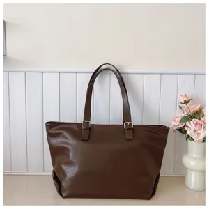 Dettaglio della borsa tote marrone scuro con fibbie argentate e trama in ecopelle lucida