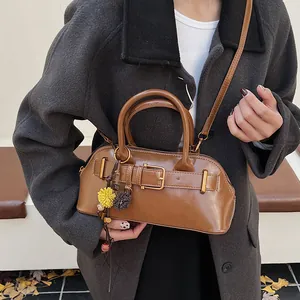 Retro caramel brown leather shell bag with gold buckle and fuzzy pompom charms