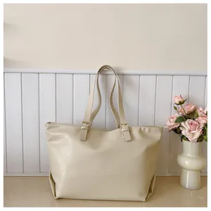 Dettaglio della borsa tote in pelle PU color crema con trama fine e fibbia dorata