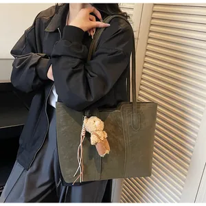 Dettaglio borsa shopper in camoscio verde oliva con ciondolo a orsetto e cuciture