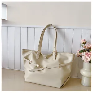 Dettaglio di una borsa tote bianco crema con texture in pelle e fibbie dorate