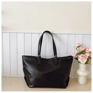 Dettaglio della borsa tote nera con doppi spallacci e fibbie metalliche dorate eleganti