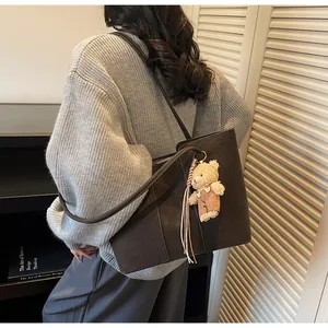 Dettaglio della grande borsa tote in pelle scamosciata marrone scuro con ciondolo a orso
