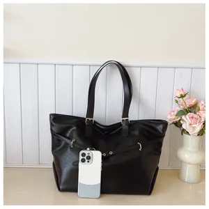 Dettaglio della borsa tote in pelle nera con cinturini laterali e fibbie metalliche