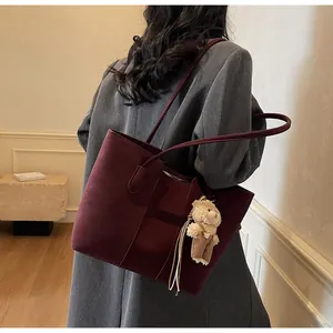 Dettaglio borsa tote in pelle opaca bordeaux con ciondolo a orsetto morbido