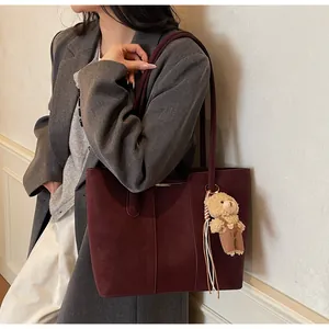 Dettaglio della borsa tote bordeaux in finta pelle scamosciata con ciondolo a orso