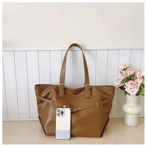 Borsa tote marrone con confronto dimensioni smartphone che mostra la capienza