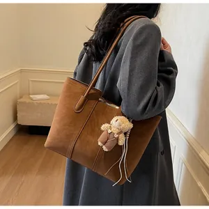 Vista dettagliata di una borsa tote marrone vintage con un simpatico ciondolo a forma di orsetto