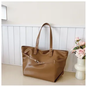 Dettaglio della trama della borsa tote in pelle marrone con cinturino decorativo e anello