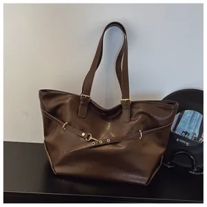 Vista macro della borsa tote in pelle PU marrone scuro con fibbia dorata e texture vintage