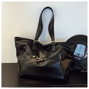 Dettaglio della borsa tote in pelle nera lucida con eleganti fibbie metalliche dorate