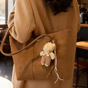 Grande borsa tote marrone retrò con ciondolo a orsetto indossata da una modella