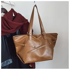 Dettaglio di una borsa tote in pelle marrone con fibbia dorata e texture morbida