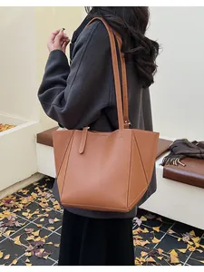 Close-up of brown textured leather tote bag featuring contrast white stitching and long strap