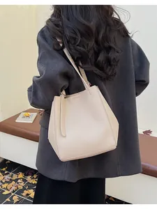 Close-up of beige lychee leather bucket bag showing soft texture and shoulder strap
