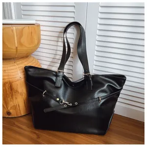 Dettaglio ravvicinato di una grande borsa tote nera con trama fine e fibbie metalliche