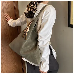Macro detail of olive green suede hobo bag with colorful woven tassel charm decoration