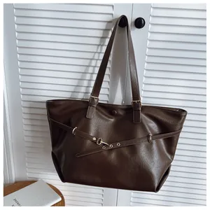 Dettaglio della pelle PU marrone scuro di una borsa tote con eleganti fibbie in metallo