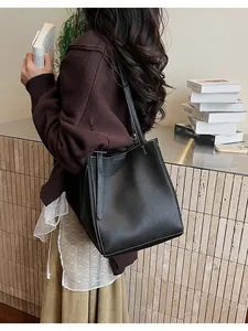 Close-up of black leather tote bag with white contrast stitching and lychee texture