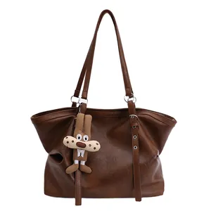 Retro brown oversized faux leather tote bag with metal buckle straps and plush charm