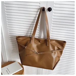 Dettaglio della borsa tote color caramello con cinturino decorativo e fibbia in metallo