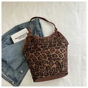 Detail of leopard print tote bag with brown leather straps next to a denim jacket