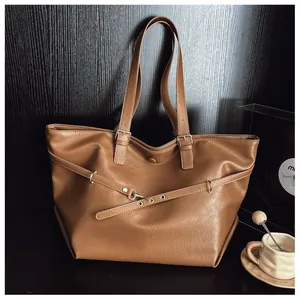 Dettaglio borsa tote in pelle marrone caramello con fibbie in metallo e tracolla