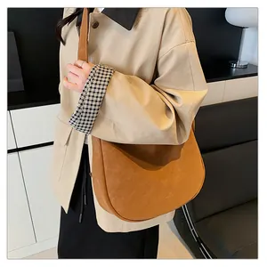 Brown suede saddle bag shown on model wearing a beige coat for a stylish fall daily look