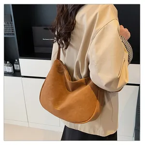 Detail view of large brown suede hobo bag worn over the shoulder showing soft texture