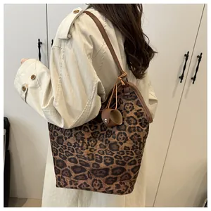 Detail view of large leopard print tote bag with brown leather straps on a female model