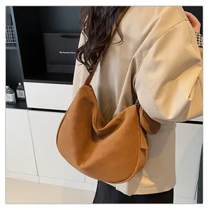 Close-up of matte brown suede hobo bag with gold logo detail and hanging side tassels