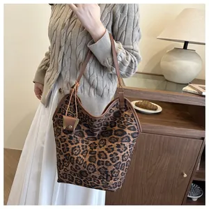 Close-up of leopard print tote bag featuring a leather strap and mini charm pouch detail