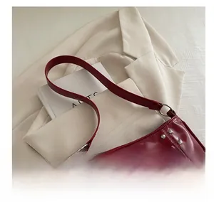 Close-up of wine red glossy patent leather shoulder bag with silver rivet details