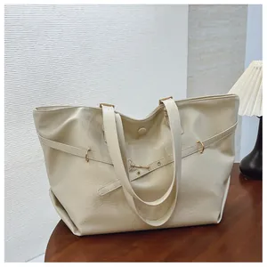 Dettaglio della borsa tote beige in finta pelle con hardware dorato su tavolo
