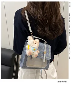 Détail d'un sac à dos en denim bleu clair avec bordure en cuir argenté et charm ours en peluche