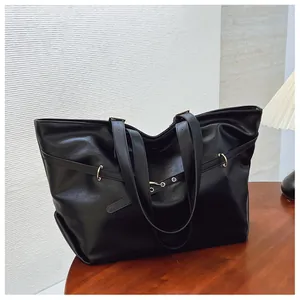 Dettaglio di una borsa tote nera in ecopelle con trama morbida su tavolo di legno