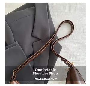 Detail of comfortable brown leather shoulder strap with neat stitching and metal buckle