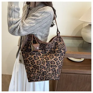 Detail shot of leopard print canvas tote bag with brown leather handles on a model