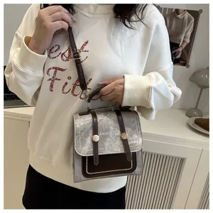 Détail du sac à dos rétro en tissu gris avec sangles en cuir brun et boucles en métal