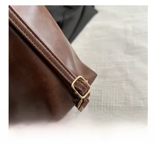 Detail of adjustable gold metal buckle and neat stitching on dark brown leather strap