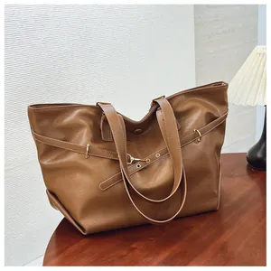 Vista dettagliata della grande borsa tote marrone con dettagli metallici su tavolo in legno