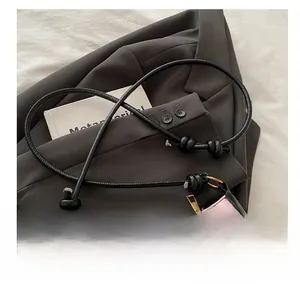 Close-up of pink textured underarm bag featuring black bow detail and rope shoulder strap