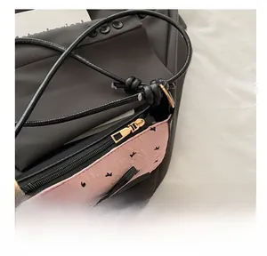 Close-up of smooth gold metal zipper and bow detail on pink textured crossbody bag