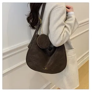 Detail of dark brown suede crescent bag with matching round coin purse and gold logo