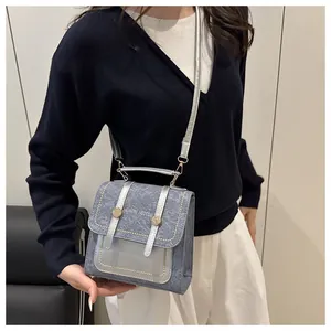 Détail d'un sac à bandoulière bleu denim avec garniture argentée et bandoulière amovible