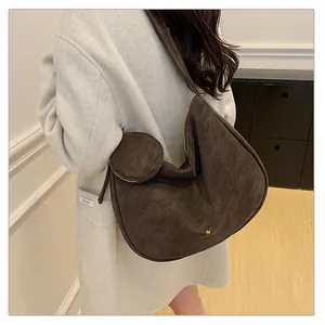 Detail of dark brown faux suede crescent bag with white stitching and round pouch