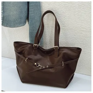 Dettaglio della borsa tote marrone scuro con occhielli in metallo e cinturino decorativo
