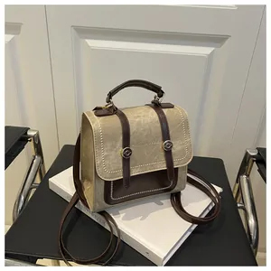 Détail du mini sac à dos vintage en toile avec garniture en cuir marron sur un livre