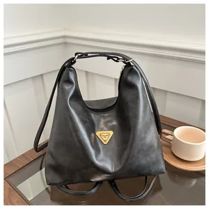 Close-up of black leather tote bag with gold triangle logo on a wooden table